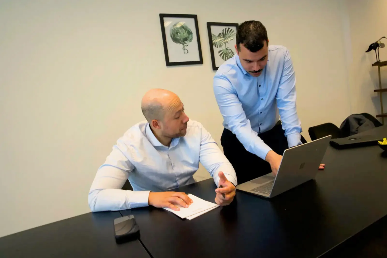 Two colleagues reviewing performance and progress together on a laptop